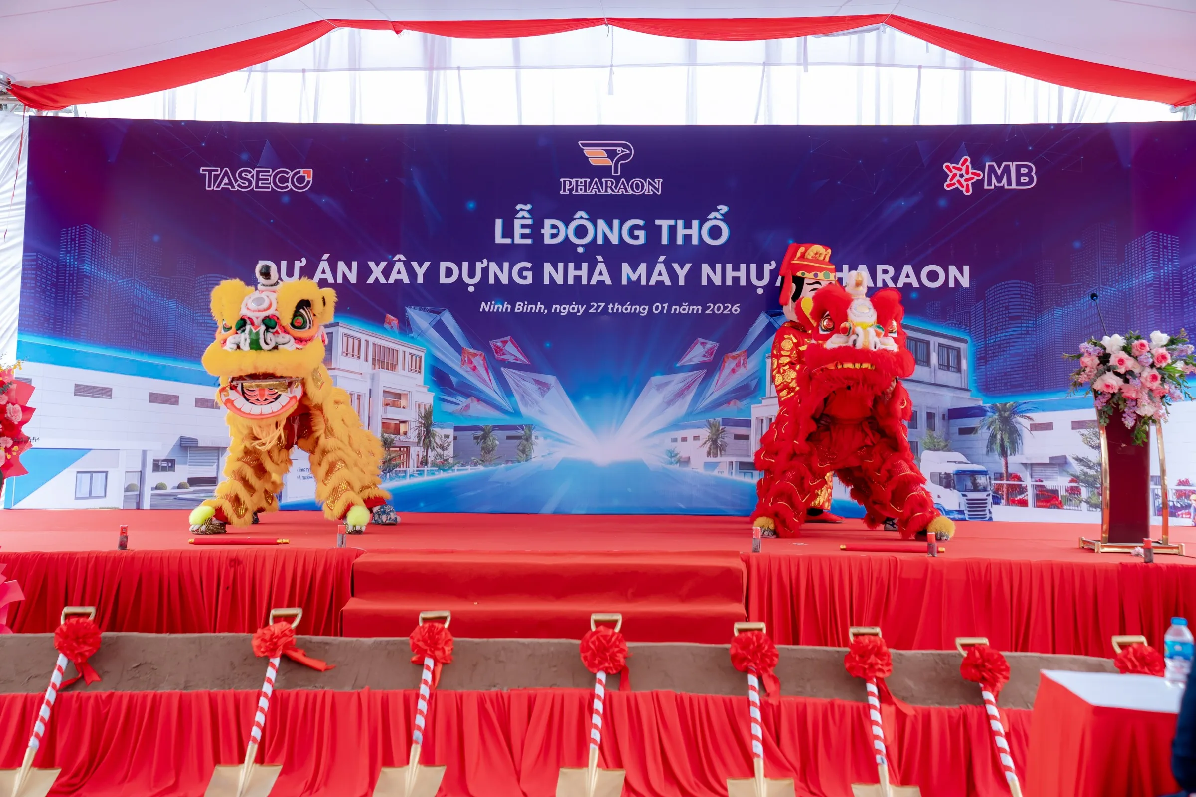 Lion dance on stage in front of the project backdrop, ceremonial shovels in the foreground