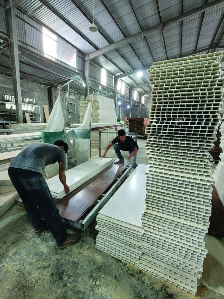 Extruded PVC panel profiles stacked at the PHARAON plant, hollow cell structure visible at the cut ends
